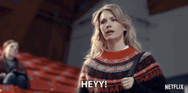 a woman wearing a sweater that says heyy