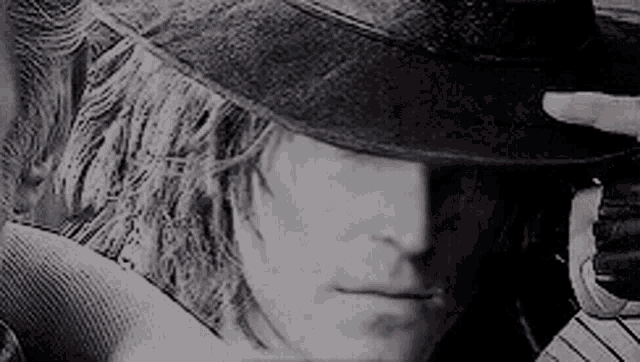 a man wearing a hat and gloves is looking at something in a black and white photo .