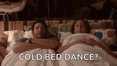 a man and a woman are laying in bed with the words `` cold bed dance '' written on the screen .