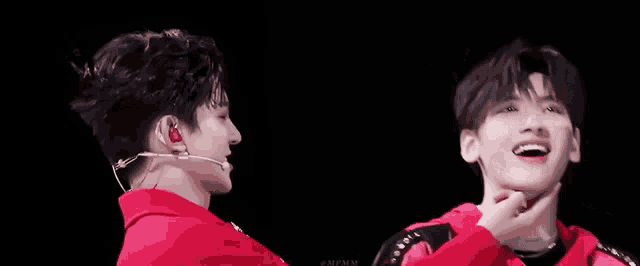 two young men are standing next to each other and looking at each other in a dark room .