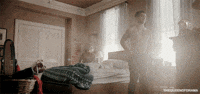 a shirtless man standing in a bedroom next to a bed