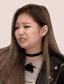 a close up of a girl wearing a choker and a leather jacket making a funny face .