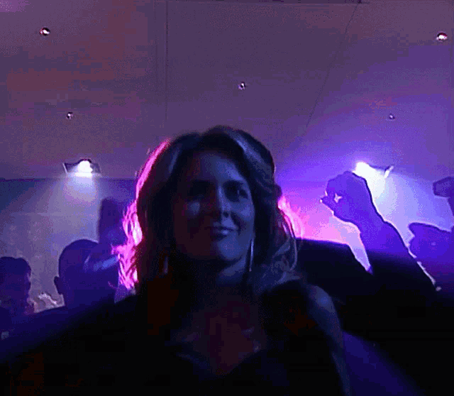a woman is dancing in a club with purple lights