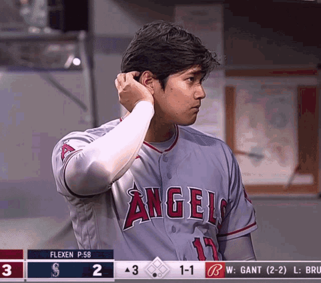 a baseball player for the angels adjusts his ear during a game