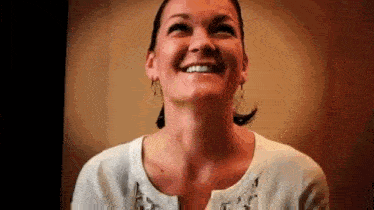 a woman is smiling and looking up at the camera while wearing earrings .