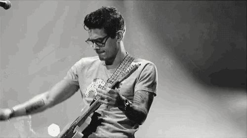 a man is playing a guitar in front of a microphone on a stage in a black and white photo .