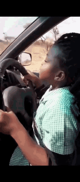a young girl is driving a car with her eyes closed