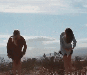 a man and a woman are standing next to each other in the dirt .