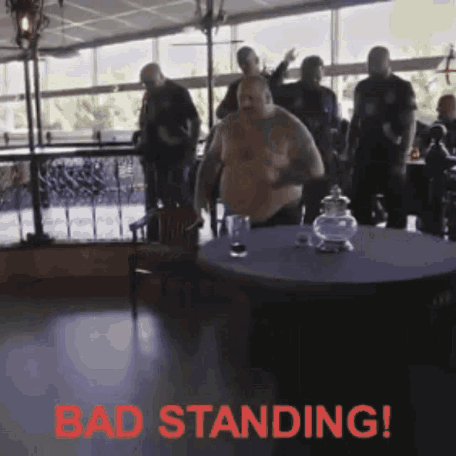 a group of men are standing around a table with the words bad standing written in red