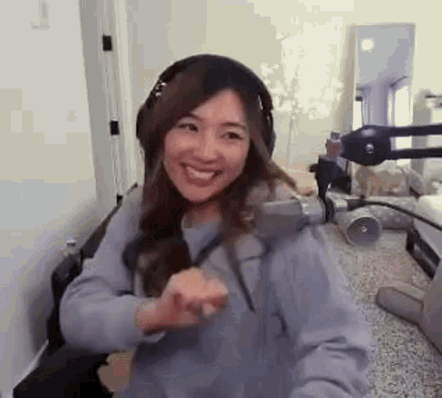 a woman wearing headphones is sitting in front of a microphone in a room and smiling .