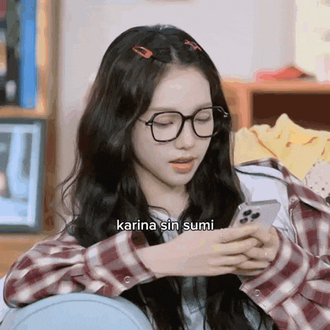 a girl wearing glasses is looking at her phone .