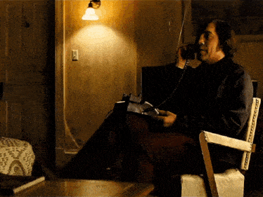 a man sitting in a chair talking on a telephone