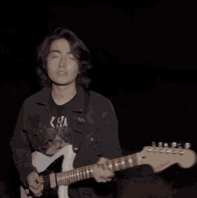 a young man playing a guitar with a t-shirt that says ' ka ' on it