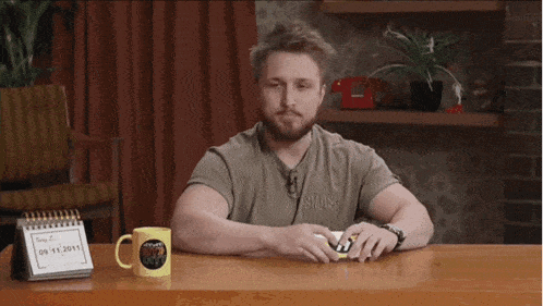 a man sitting at a table with two cups and a calendar that says 09 11 2011