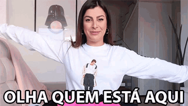 a woman wearing a white shirt with a picture of a man and the words olha quem esta aqui on the bottom