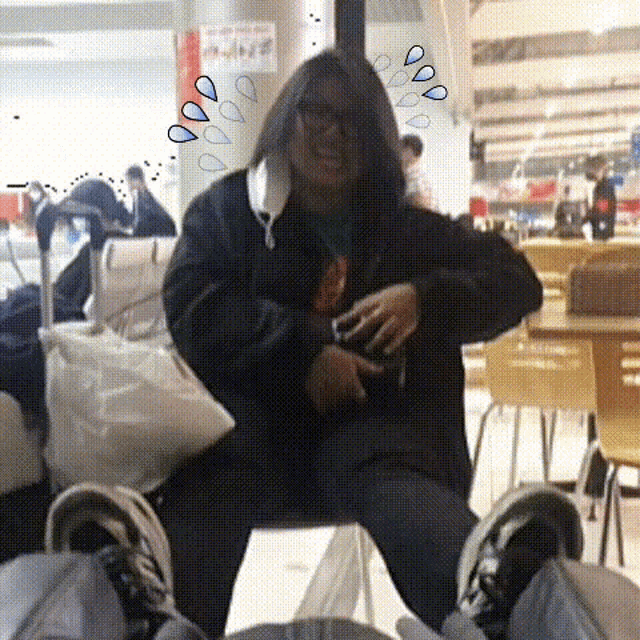 a person wearing a hooded jacket is sitting on a table with their legs crossed