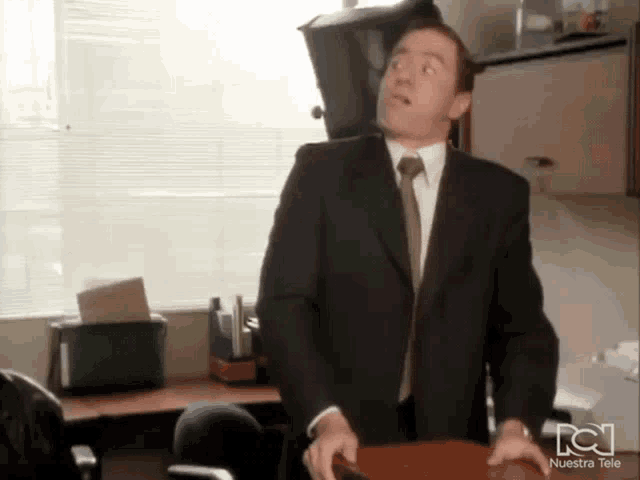 a man in a suit and tie is standing in front of a nuestra tele logo