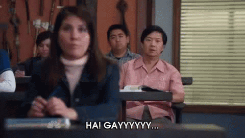 a group of people are sitting at desks in a classroom and a woman is sitting in front of them .