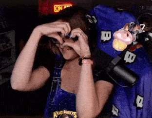 a woman making a heart with her hands in front of a microphone