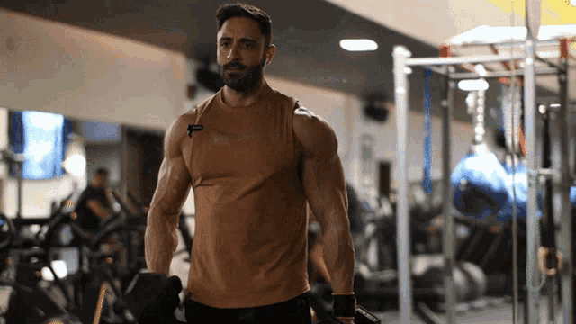 a man in a tank top with the word reebok on it is lifting dumbbells in a gym