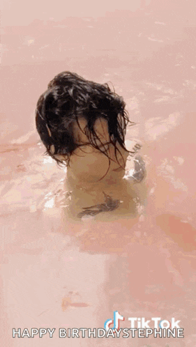 harry styles is wearing a pink suit and blowing a kiss while standing on a stage .