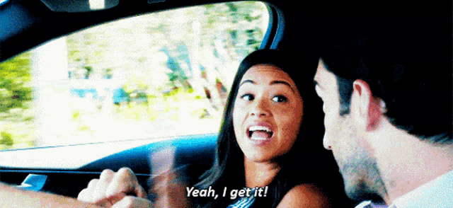 a man and a woman are sitting in a car and the woman is saying yeah i get it