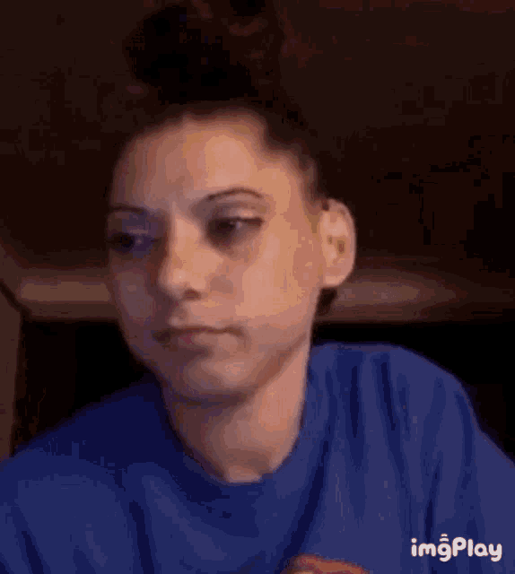 a woman in a blue shirt is making a funny face while looking at the camera .
