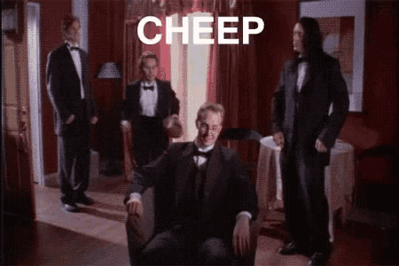 a group of men in tuxedos are standing around a man in a chair with the word cheep below him