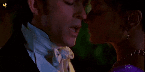 a man and woman are kissing each other in a dark room .