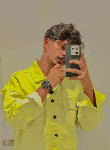 a man in a yellow jacket is taking a picture of himself in the mirror
