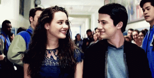 a boy and a girl are standing next to each other in a hallway looking at each other .