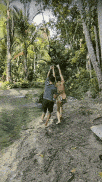 a woman in a bikini is being pulled by a man on a rope swing