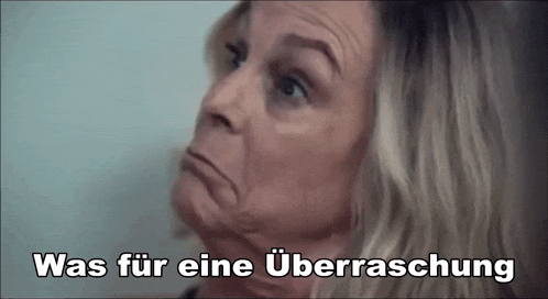 a close up of a woman 's face with the words was fur eine überraschung written above her .