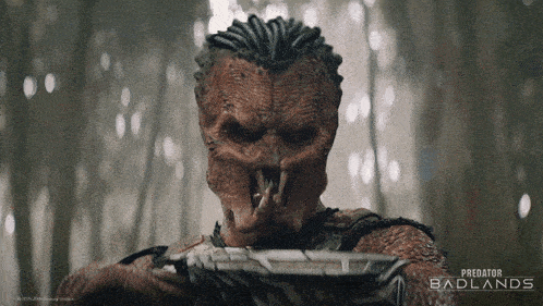 a poster for predator badlands shows a monster holding a gun