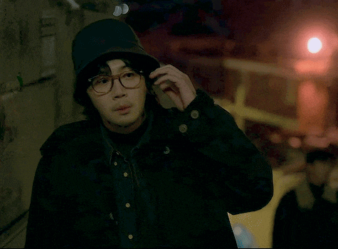 a man wearing glasses and a hooded hat is talking on a cell phone