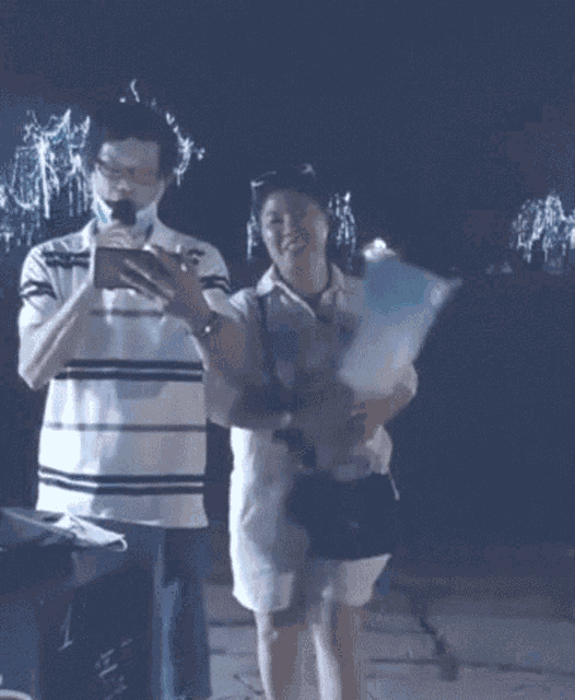 a man and a woman are standing next to each other holding balloons .