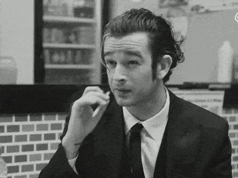 a man in a suit and tie smoking a cigarette in a black and white photo