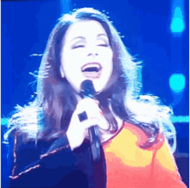 a woman singing into a microphone with a ring on her finger