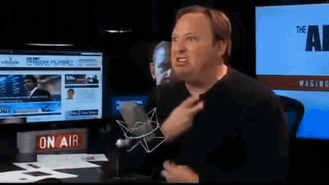 a man is talking into a microphone in front of a sign that says " on air "