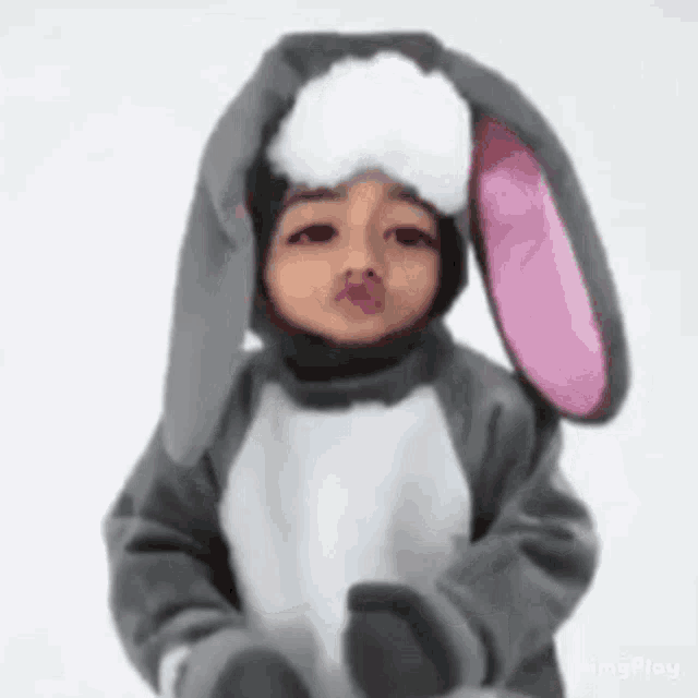 a little girl is wearing a bunny costume and making a kiss .