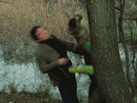 a blurry picture of a man standing next to a tree with a frog on it