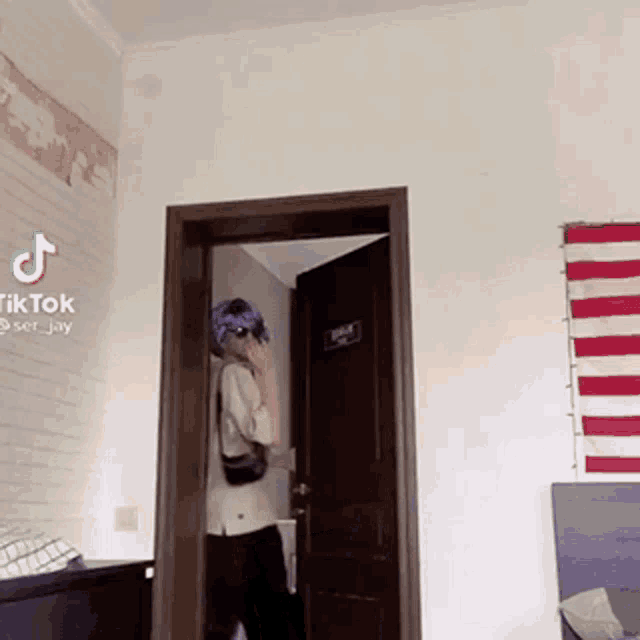 a person is standing in a doorway in a bedroom with a tiktok watermark on the bottom right corner .
