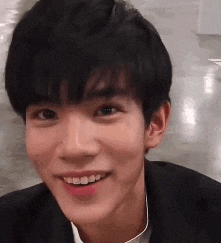 a close up of a young man 's face smiling while wearing a suit .