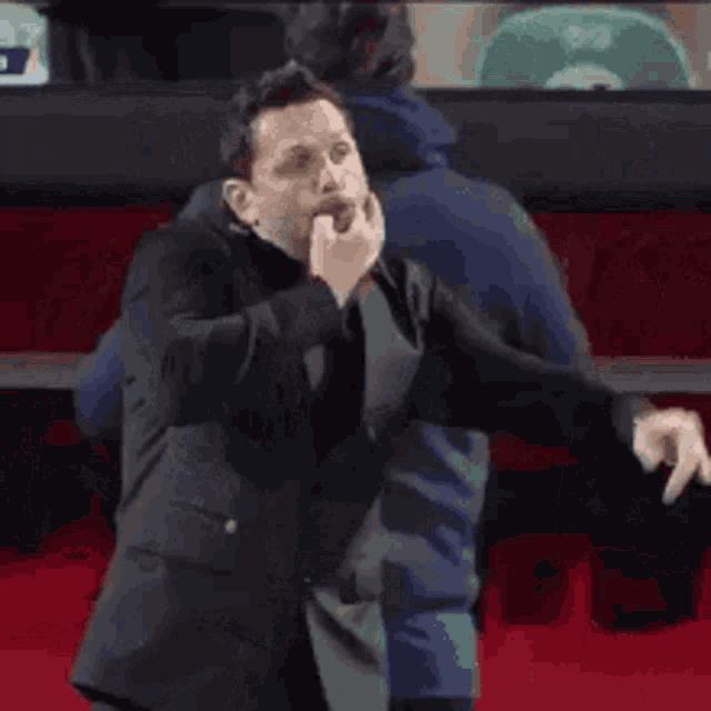 a man in a black suit is standing in a stadium .