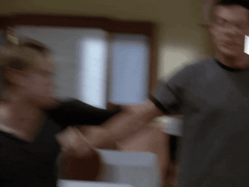 a blurry picture of a man in a grey shirt standing next to another man