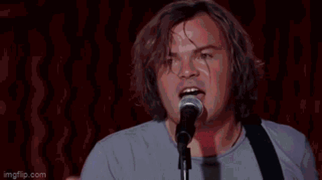 a man is singing into a microphone while holding a light .