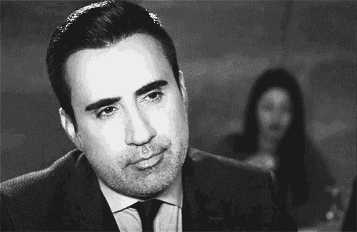 a man with a beard is wearing a suit and tie and looking at the camera .