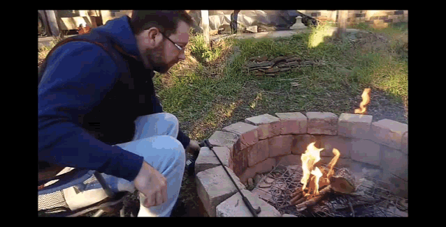 a man sitting in front of a fire pit with a shovel