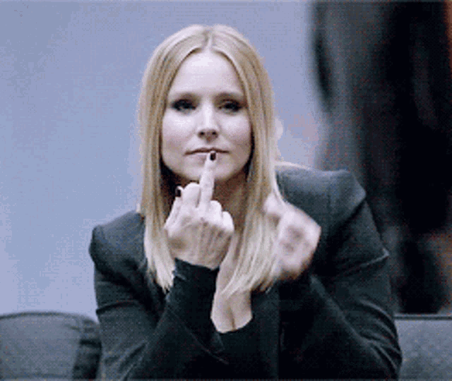 a woman in a black jacket holds her finger to her lips
