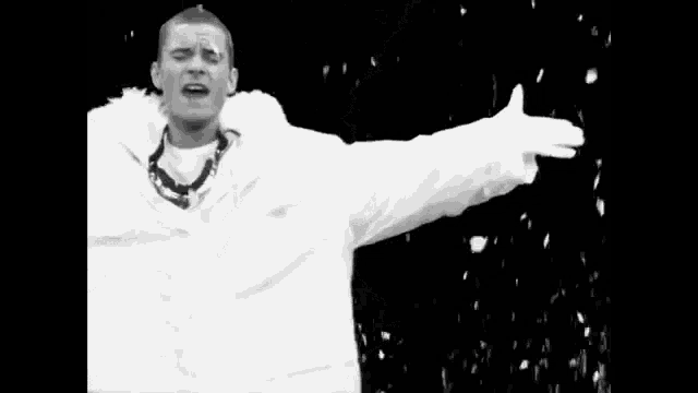 a black and white photo of a man in a fur coat and a hand reaching out .